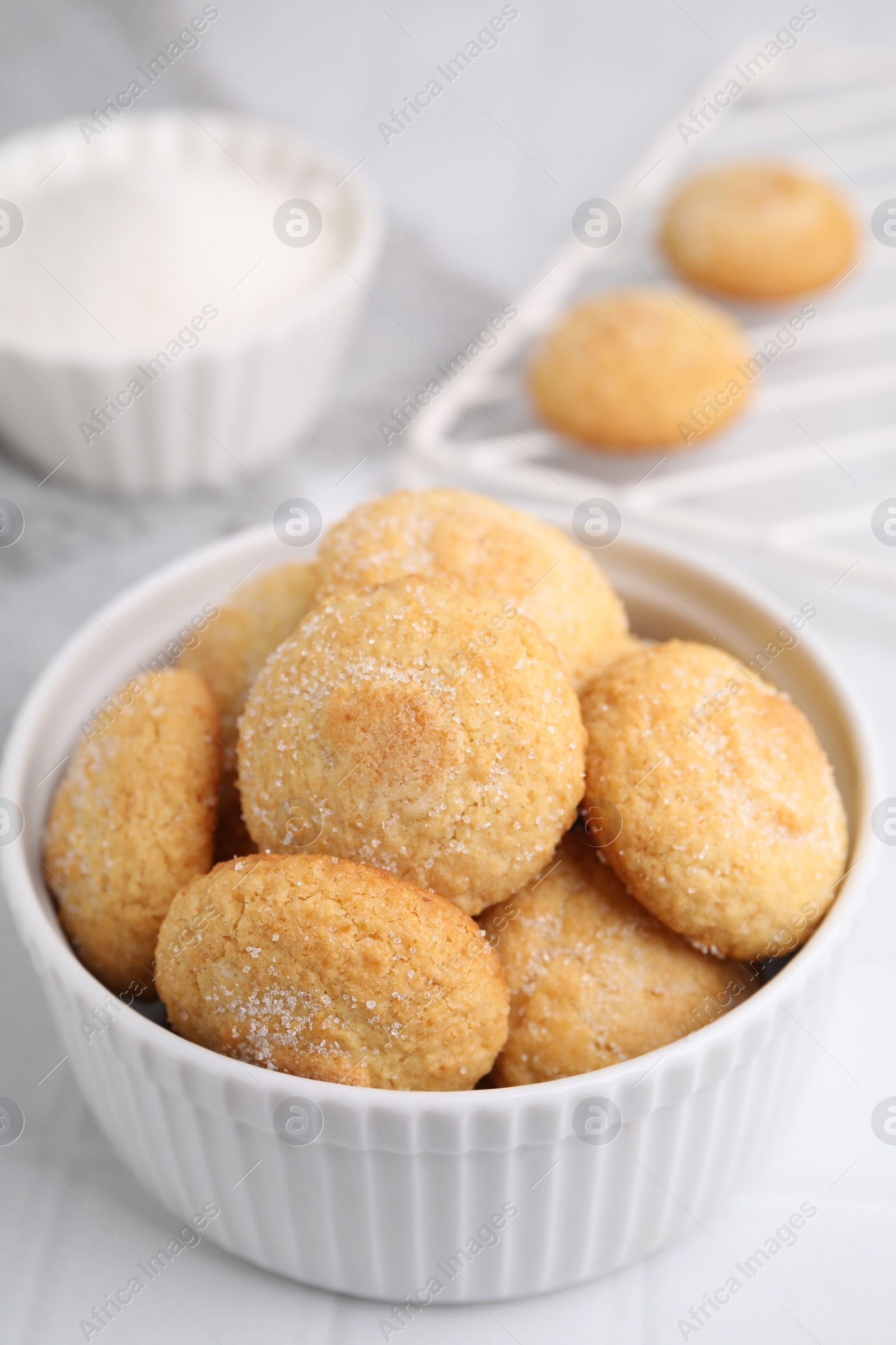 Photo of Tasty sugar cookies in bowl on white tiled table, closeup