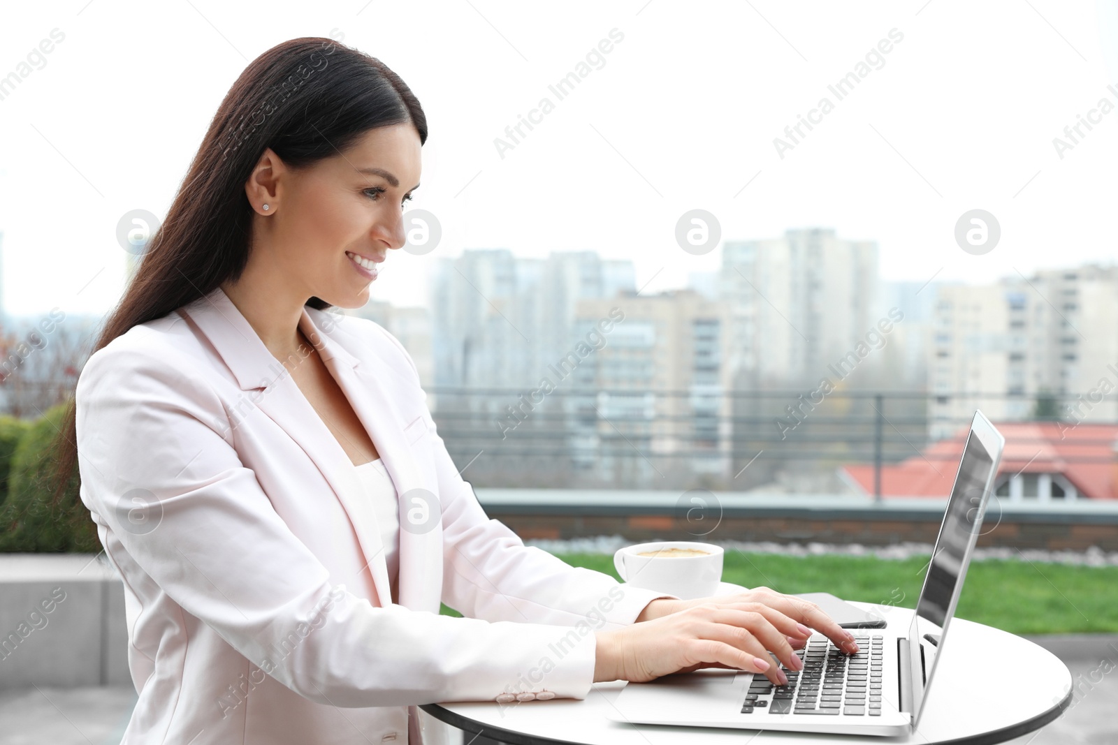 Photo of Businesswoman working with laptop in outdoor cafe. Corporate blog