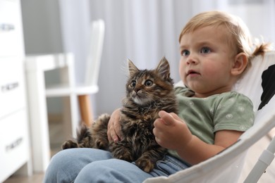 Photo of Cute little child with adorable pet sitting in armchair at home