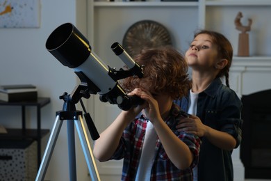Photo of Cute little children using telescope to look at stars in room