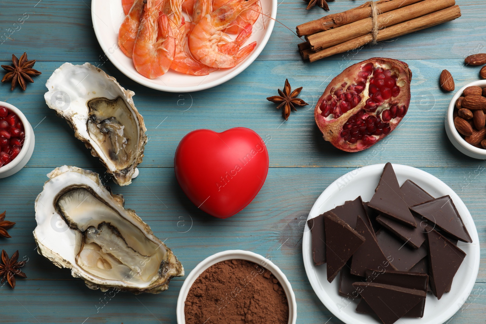 Photo of Natural aphrodisiac. Different food products and heart model on light blue wooden table, flat lay