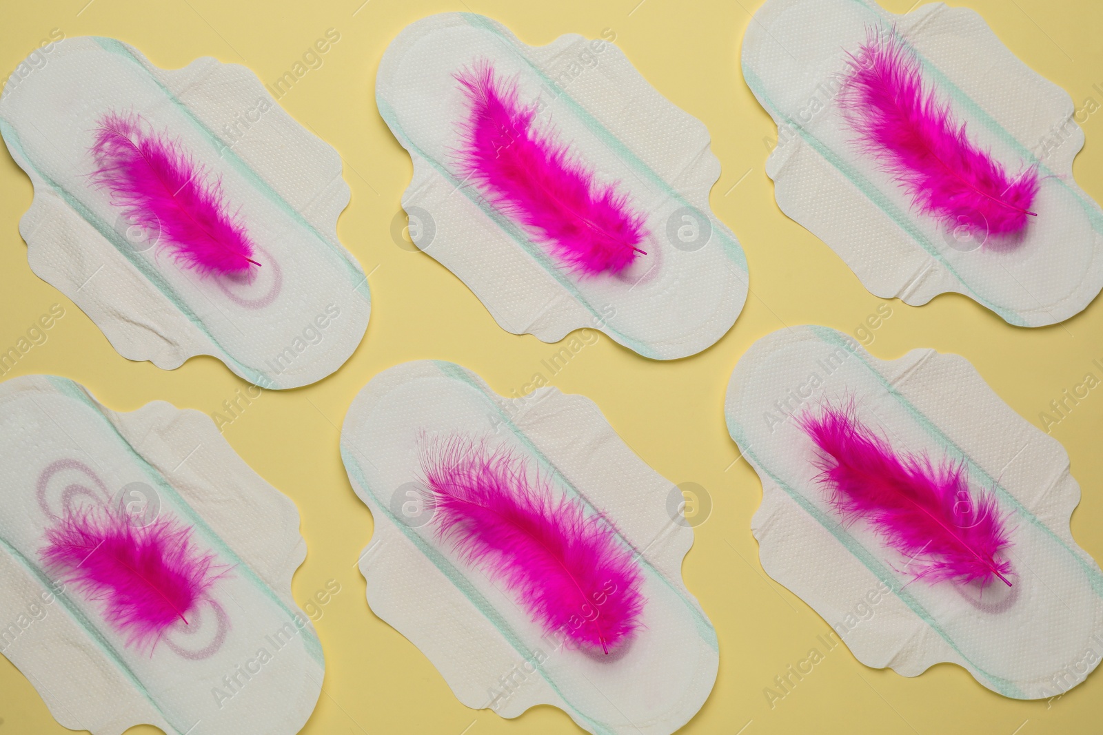 Photo of Menstrual pads with pink feathers on beige background, flat lay