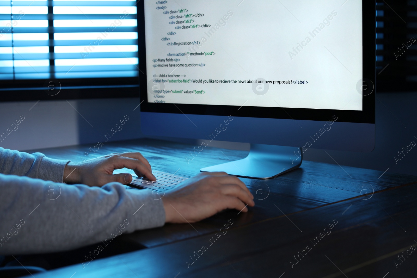 Photo of Man using computer in dark room, closeup. Criminal offence