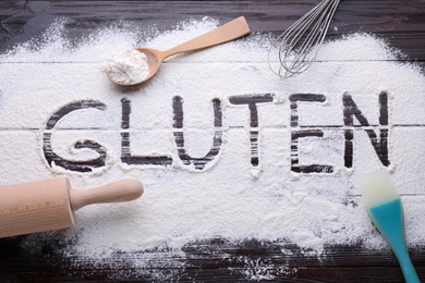 Photo of Kitchen utensils and word Gluten written with flour on dark wooden table, flat lay