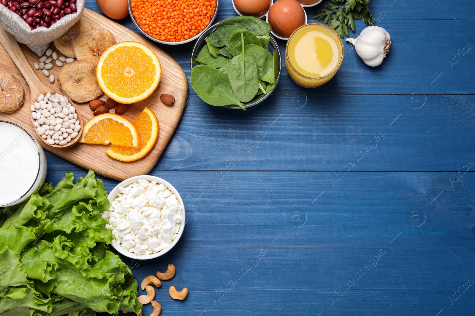 Photo of Set of natural food high in calcium on blue wooden table, flat lay. Space for text