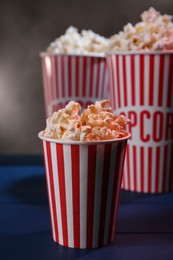 Delicious popcorn in paper cups on blue wooden table