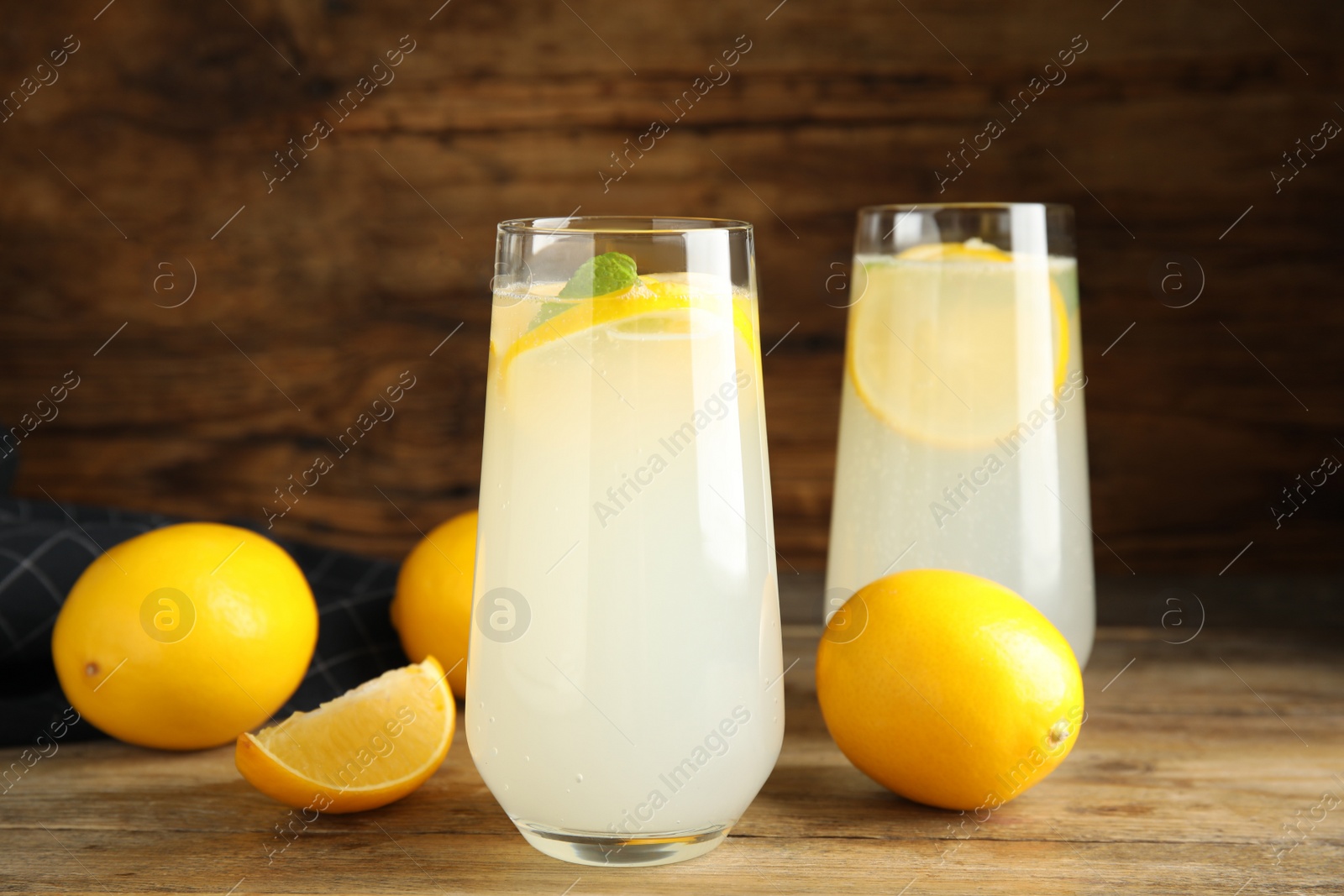 Photo of Cool freshly made lemonade and fruits on wooden table