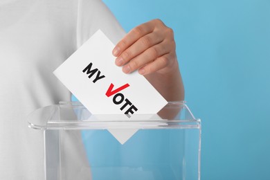 Woman putting paper with text My Vote and tick into ballot box on light blue background