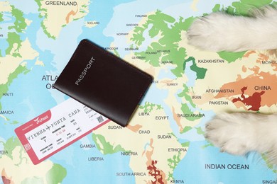 Photo of Dog lying near passport and ticket on world map, top view. Travelling with pet
