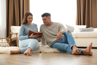 Happy couple reading book at home. Floor heating concept