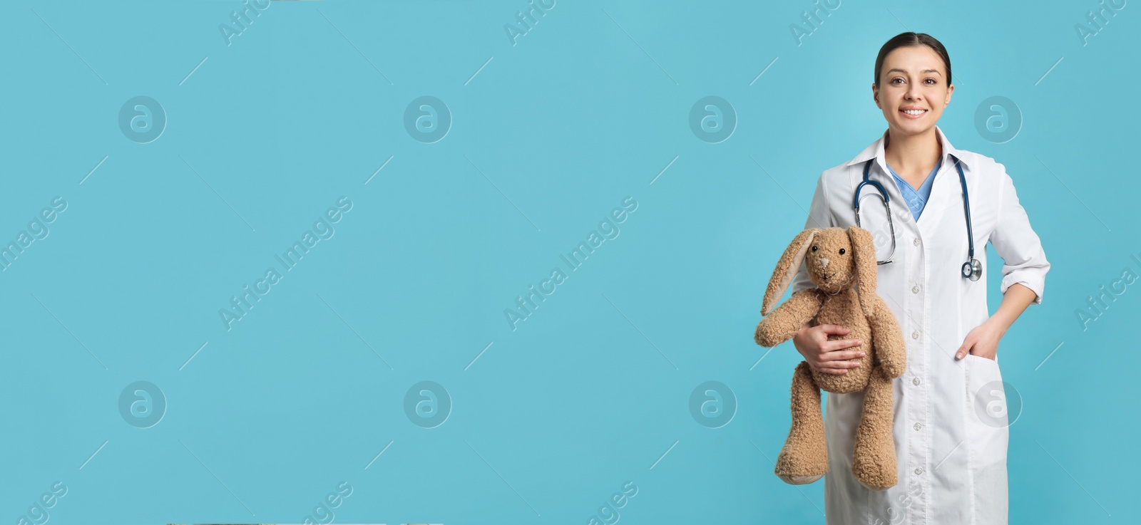 Photo of Pediatrician with toy bunny and stethoscope on turquoise background