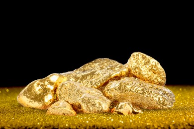 Image of Gold nuggets and gold dust on black background, space for text