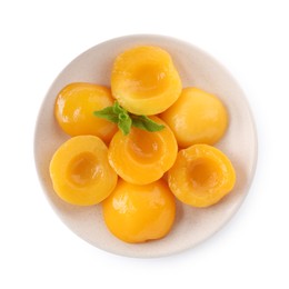 Halves of canned peaches with mint leaves isolated on white, top view