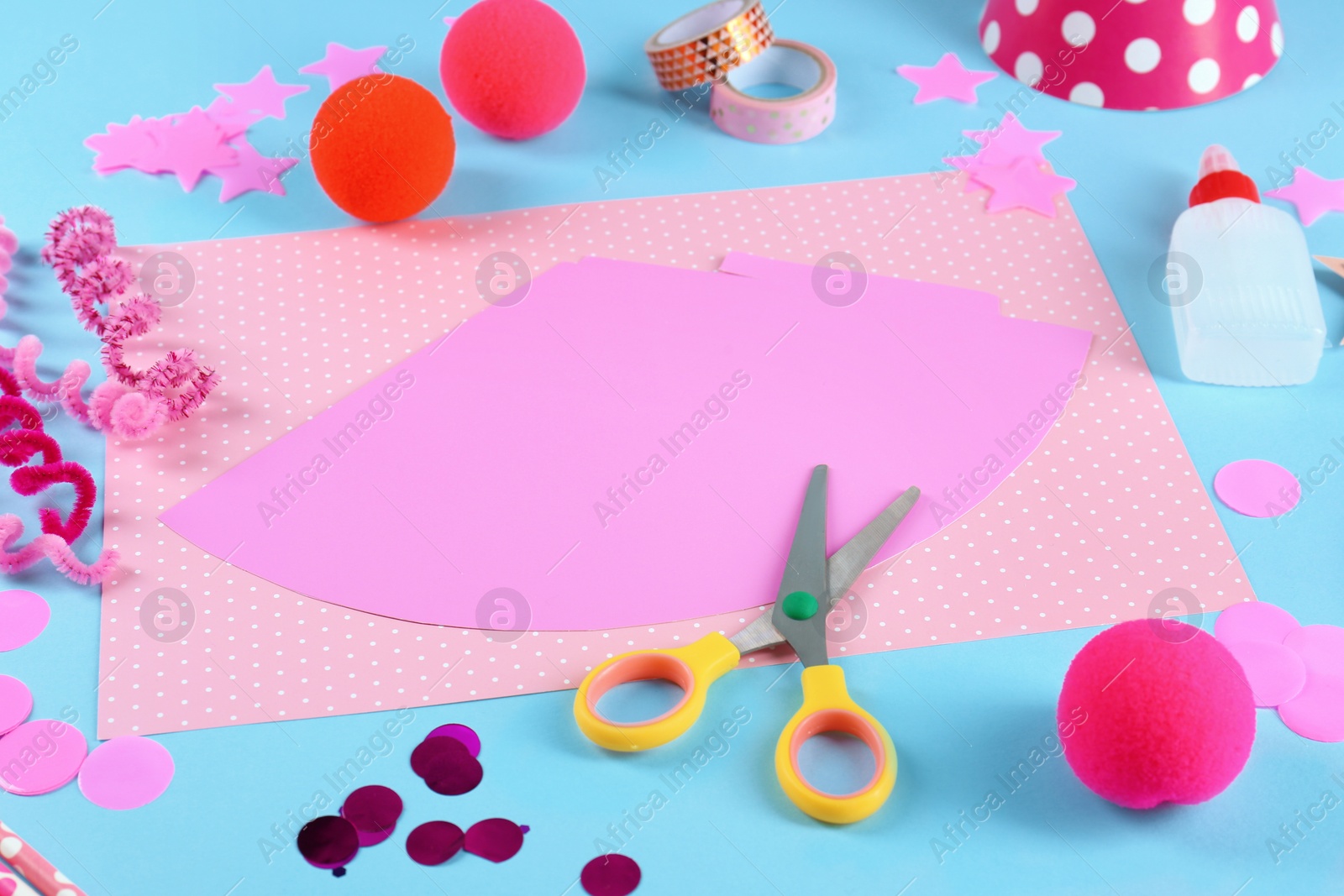 Photo of Stationery and different materials to create party hats on light blue background. Handmade decoration