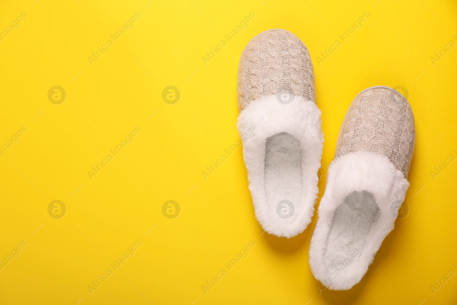 Photo of Pair of beautiful soft slippers on yellow background, top view. Space for text