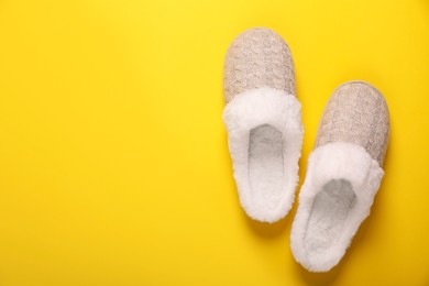 Photo of Pair of beautiful soft slippers on yellow background, top view. Space for text