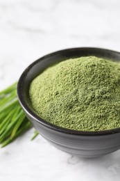 Photo of Wheat grass powder in bowl on white table, closeup