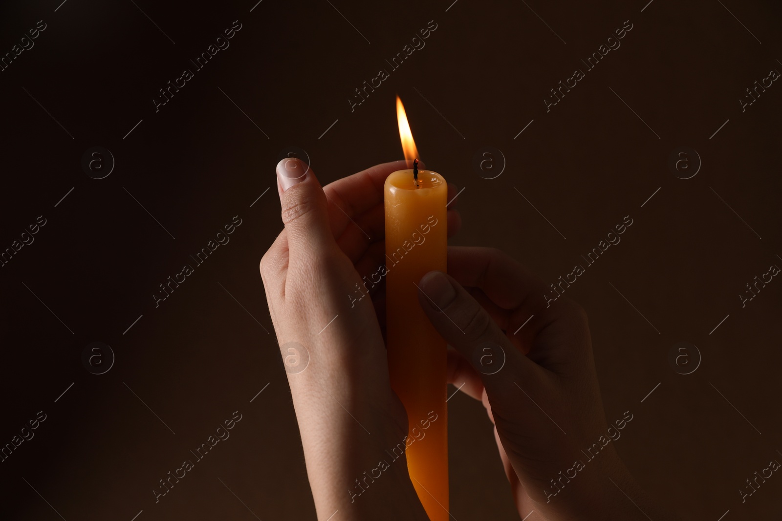 Photo of Woman holding burning church candle on dark background, closeup