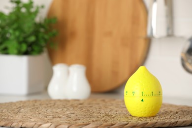 Photo of Kitchen timer in shape of lemon on wicker mat indoors. Space for text
