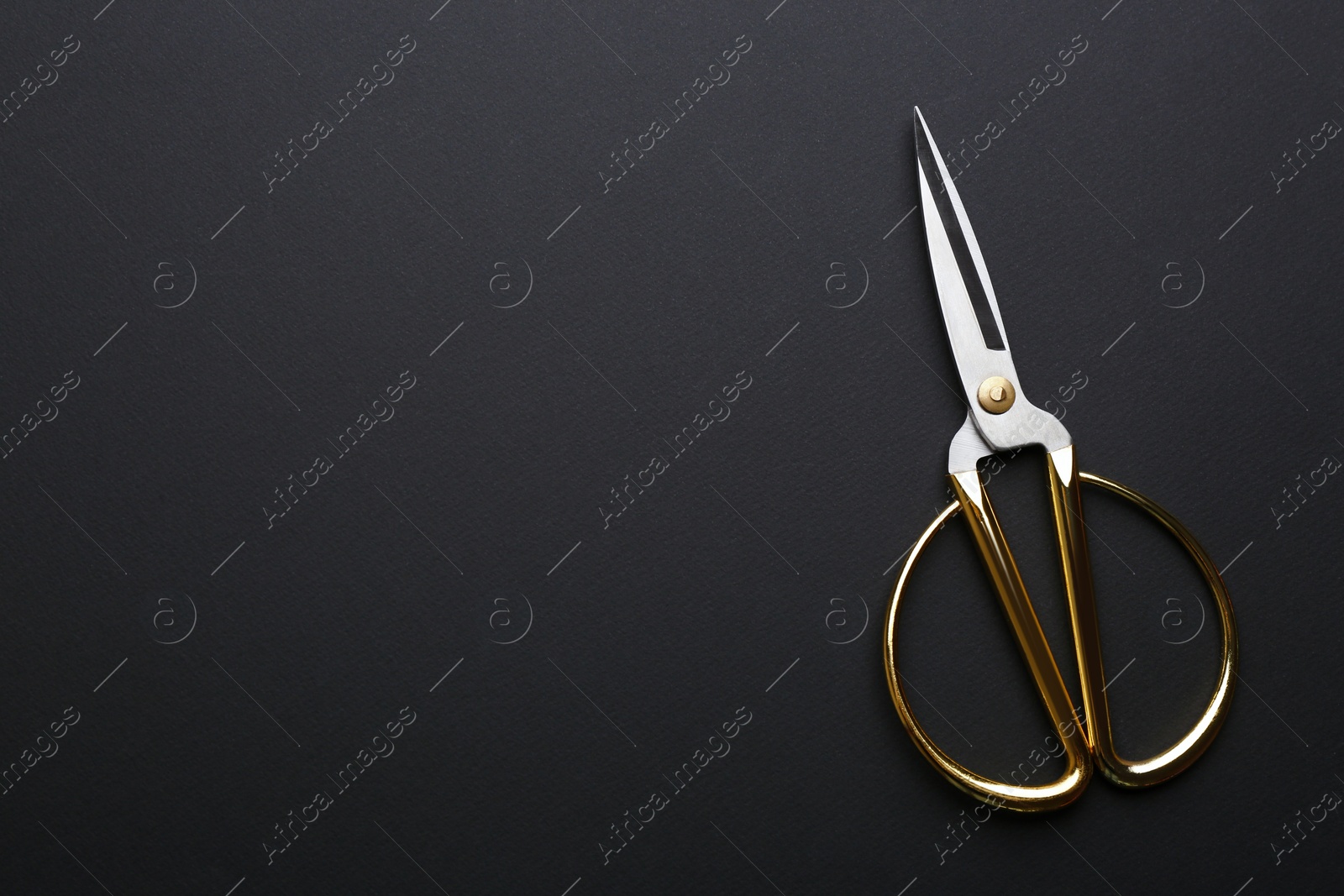 Photo of Pair of sharp scissors on dark background, top view. Space for text