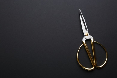 Pair of sharp scissors on dark background, top view. Space for text