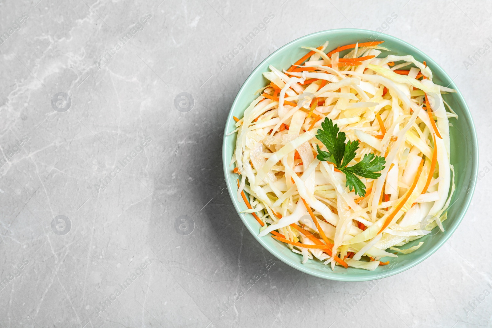 Photo of Tasty salad with cabbage and carrot on light grey marble table, top view. Space for text