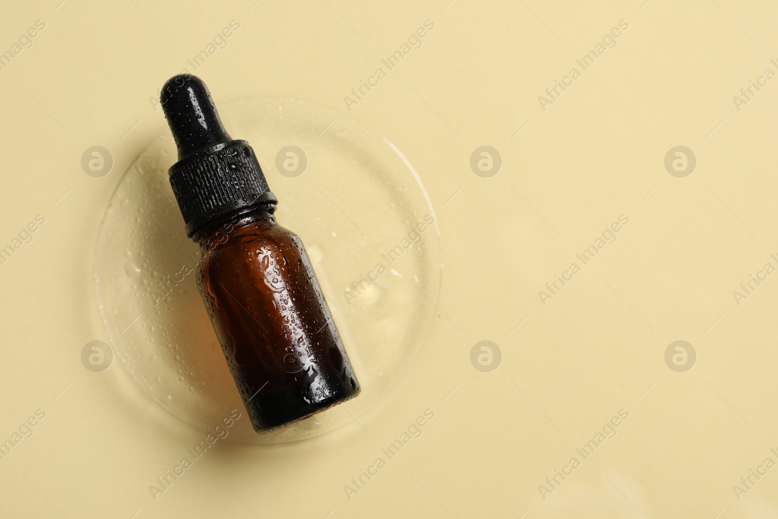 Photo of Bottle of cosmetic serum on beige background, top view. Space for text