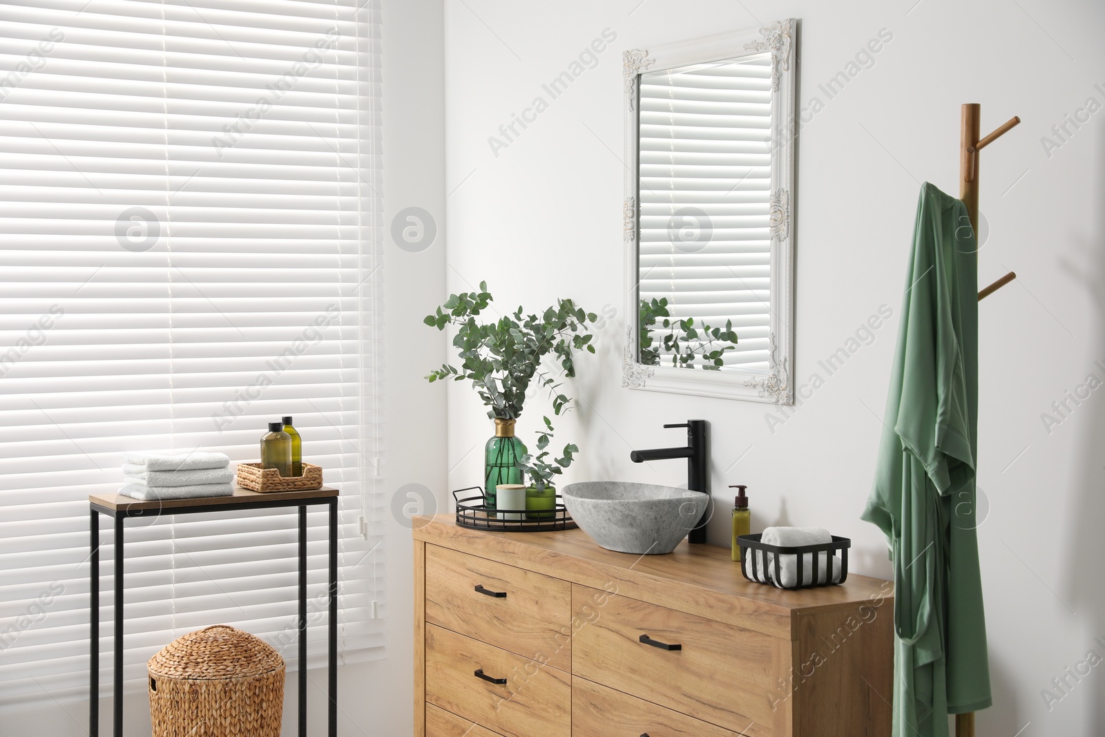 Photo of Modern bathroom interior with stylish mirror, eucalyptus branches, vessel sink and wooden vanity