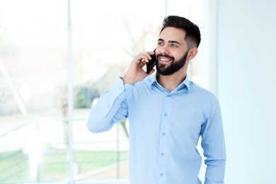 Handsome young man talking with client by phone at work. Space for text