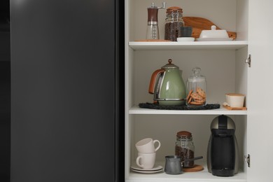 Photo of Manual coffee grinder and other appliances on shelving unit in kitchen