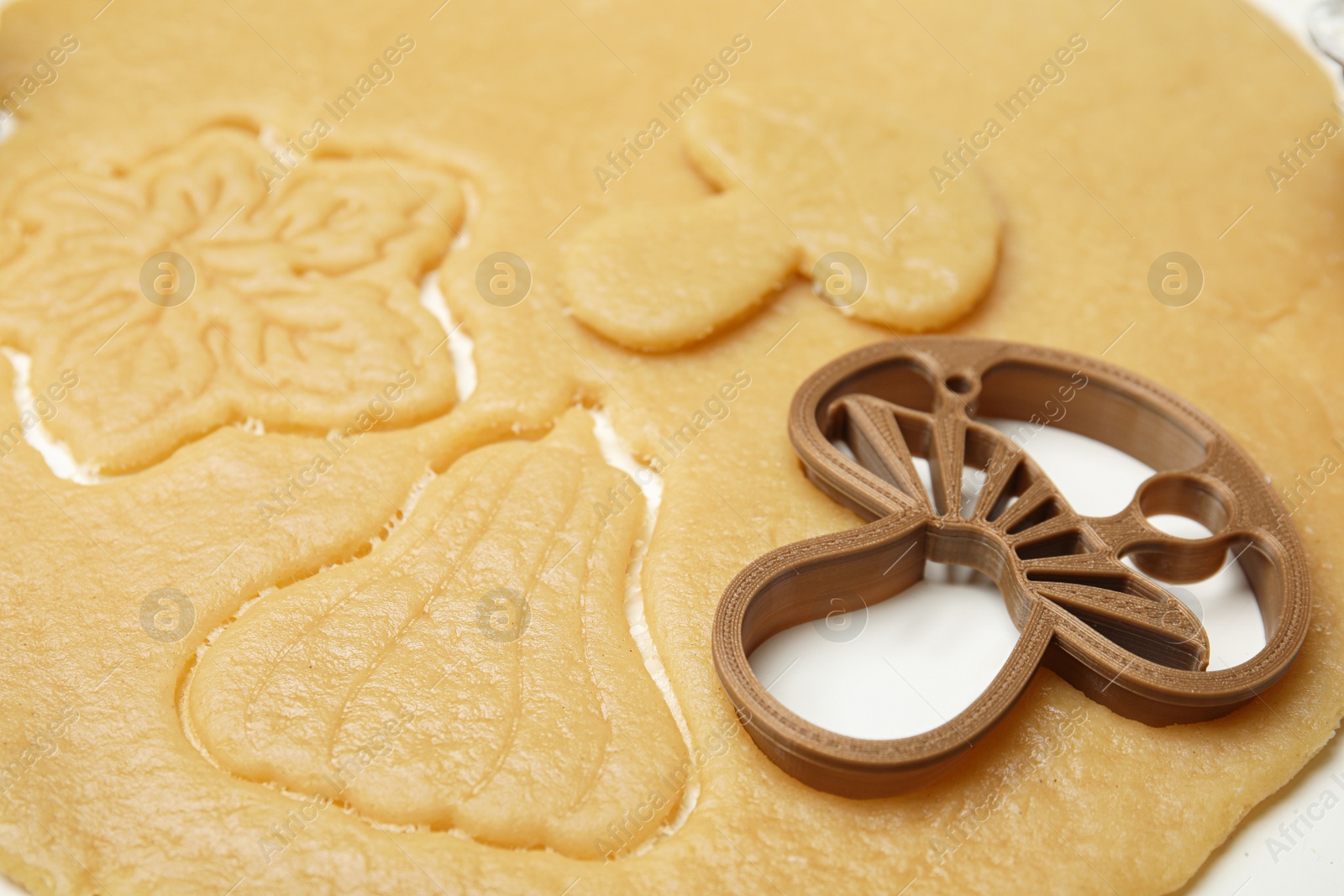 Photo of Cookie cutter and dough on white table, closeup