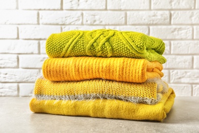 Photo of Stack of warm knitted clothes on table