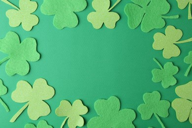 Photo of St. Patrick's day. Frame of decorative clover leaves on green background, flat lay. Space for text