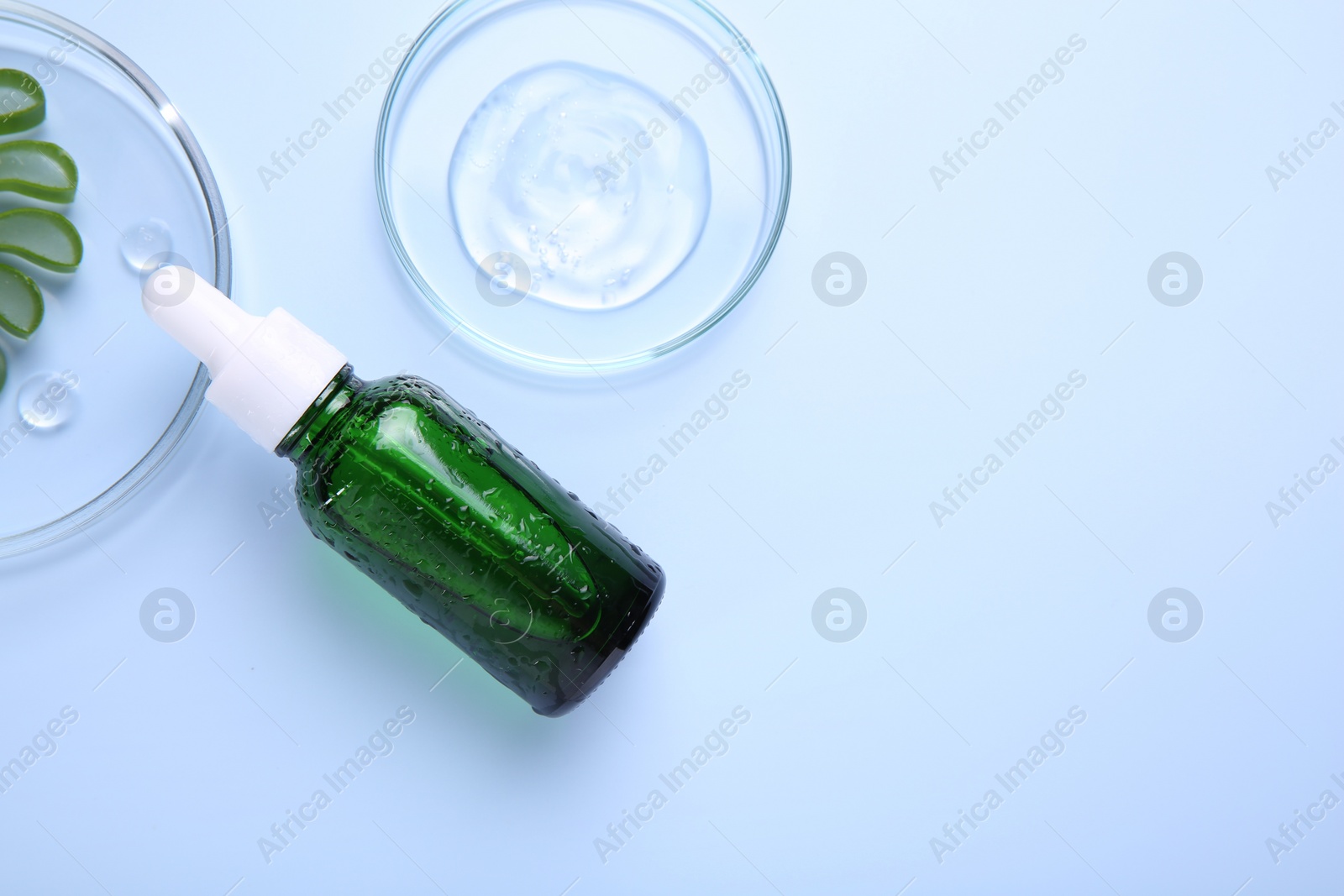 Photo of Cut aloe vera, bottle and cosmetic gel on light blue background, flat lay. Space for text