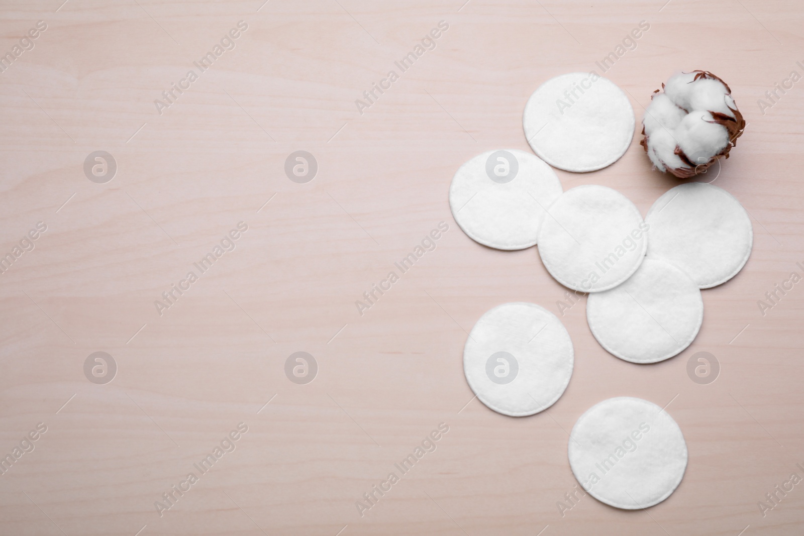 Photo of Many clean cotton pads and flower on wooden table, flat lay. Space for text