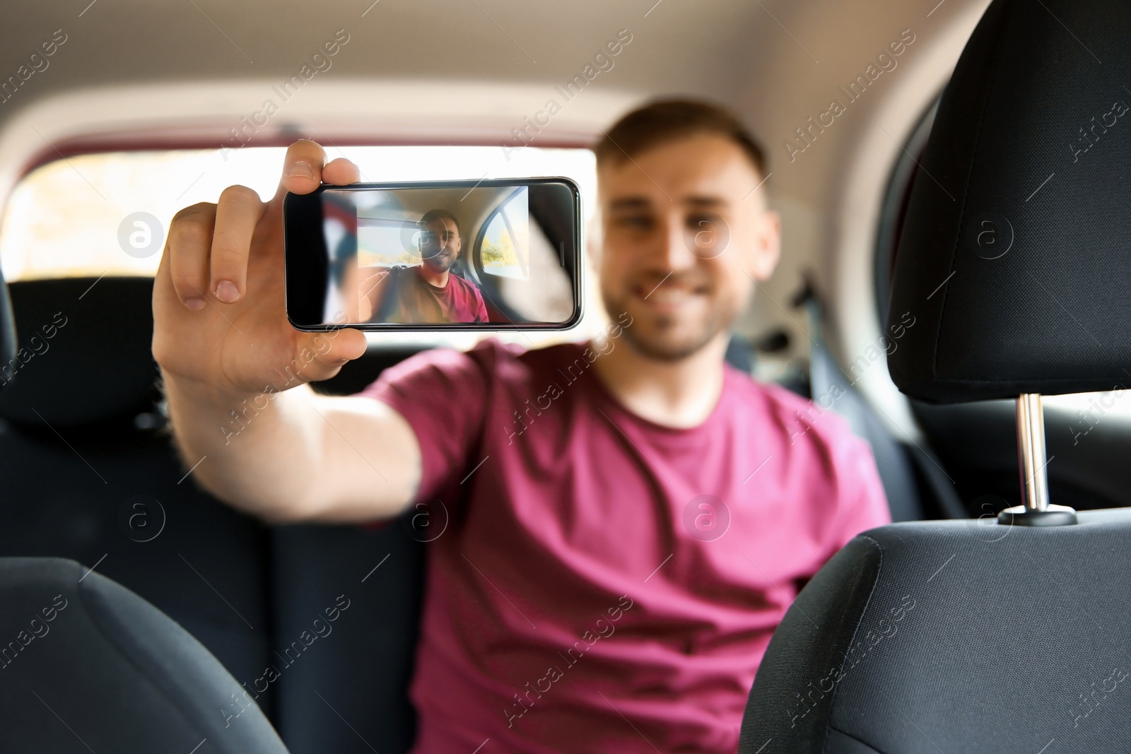 Photo of Happy young man taking selfie in car