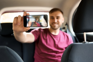 Photo of Happy young man taking selfie in car