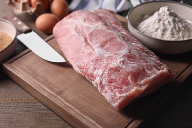 Photo of Fresh pork meat and other ingredients for cooking schnitzel on wooden table, closeup
