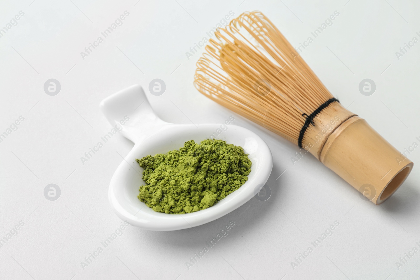 Photo of Powdered matcha tea and chasen on light background