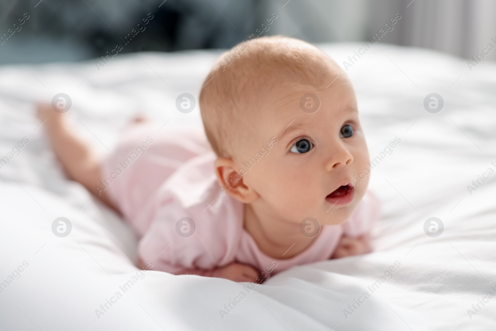 Photo of Cute little baby lying on white sheets