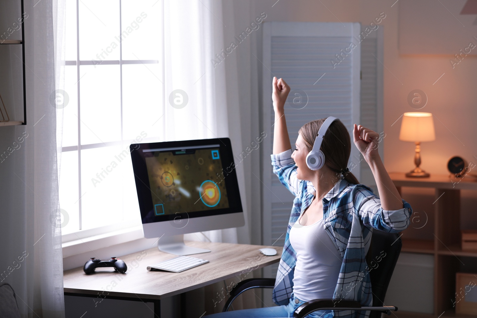 Photo of Emotional young woman playing video games at home