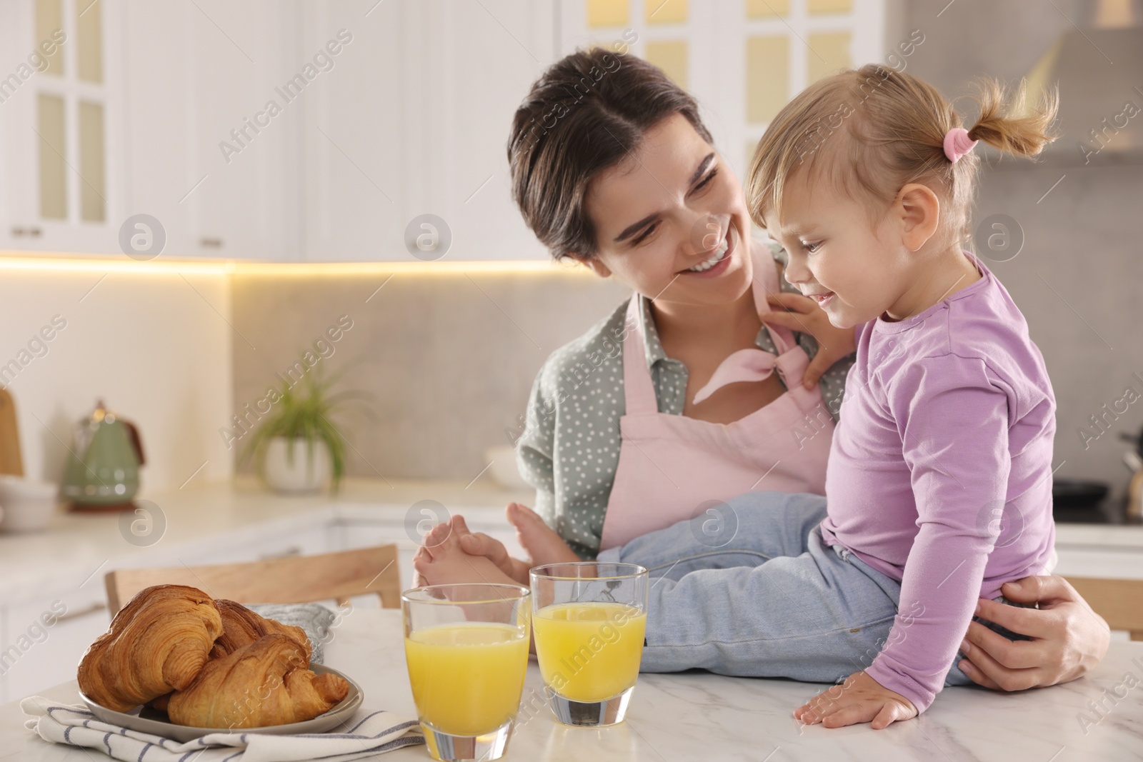 Photo of Mother and her little daughter having breakfast together in kitchen