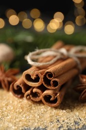 Different spices. Cinnamon sticks and cane sugar on table against blurred lights, closeup