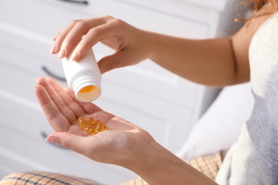 Photo of African-American woman with bottle of vitamin capsules at home, closeup