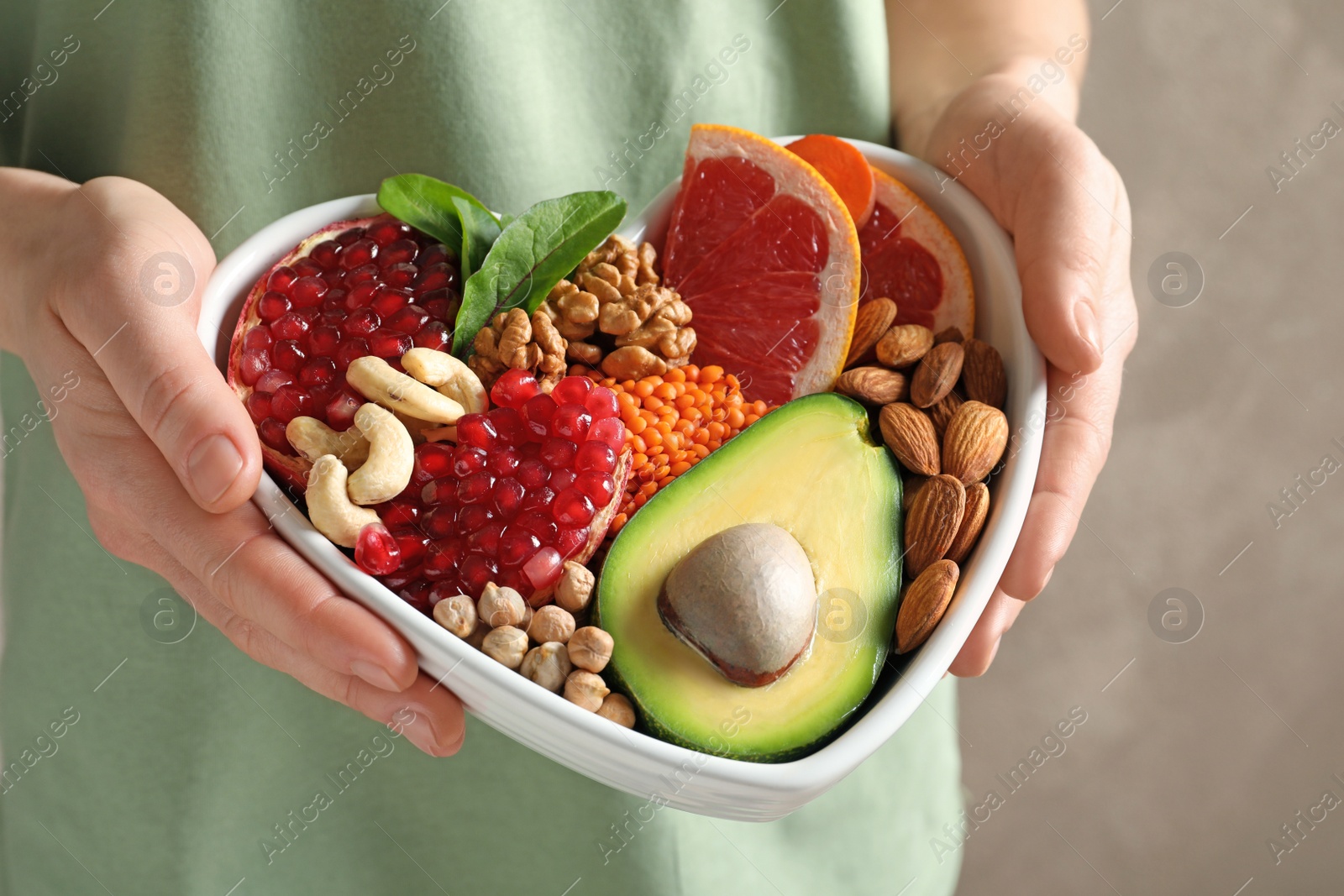 Photo of Woman holding bowl with products for heart-healthy diet, closeup