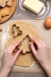 Woman making Christmas cookies with cutters at grey table, top view