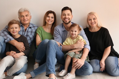 Happy family with cute kids sitting on floor near light wall