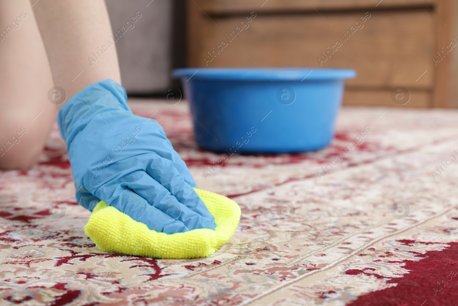 Photo of Woman in rubber gloves cleaning carpet with rag indoors, closeup. Space for text