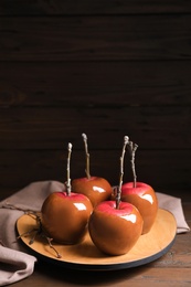 Photo of Plate with delicious caramel apples on wooden table