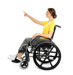 Young woman in wheelchair pointing on something isolated on white